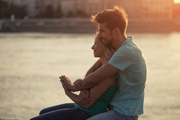 Young couple embracing while watching the sunset over the city.