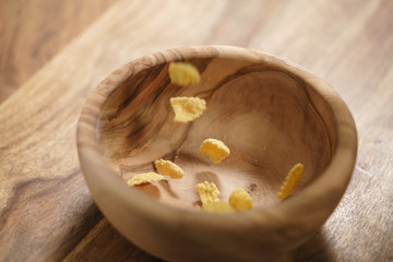 corn flakes falling into wood bowl closeup