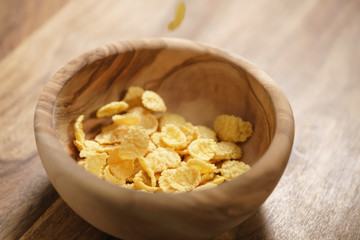 corn flakes falling into wood bowl closeup
