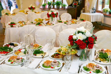 Beautifully set festive table, decorated with a bouquet of roses. The preparations for the party