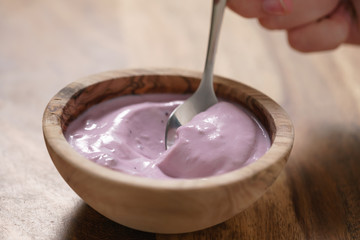 eating blueberry yogurt from wood bowl