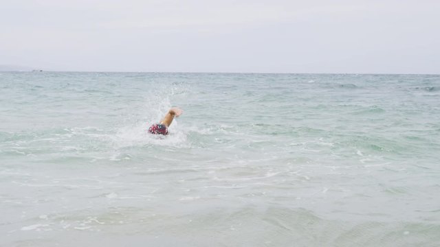 Man swimming crawl freestyle in triathlon. Man triathlete running out of water after swimming in the ocean. Male triathlete in professional triathlon outfit. RED EPIC SLOW MOTION.
