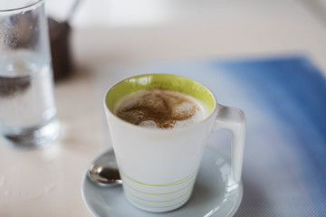 A beverage in a white and green cup on a table