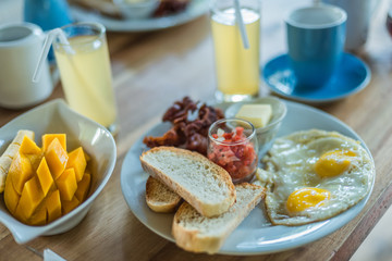 A healthy breakfast of bread, bacon, eggs and tomato salsa together with coffee and juice and fruits