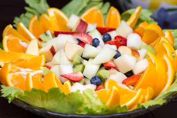 Fruit salad in a large glass bowl on a table outside in a garden