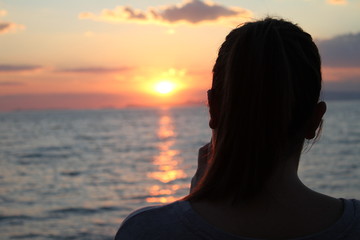 Fototapeta premium Tramonto in riva al mare con sagoma rivolta all'orizzonte