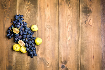 Bunches of fresh ripe grapes and figs on a wooden background Beautiful background with a branch of grapes. Dark grapes Figs