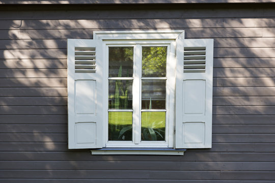 Fototapeta small vintage white window with shutters on wooden grey wall