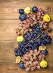 Bunches of fresh ripe grapes and figs on a wooden background Beautiful background with a branch of blue and red grapes. Figs Top view Vertical