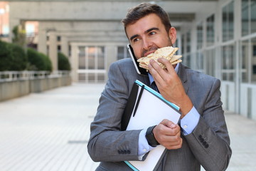 Businessman walking, eating and talking on the phone at the same time