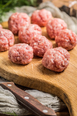Raw meatballs on the wooden cutting board.