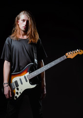 Fototapeta na wymiar Dramatic studio portrait: handsome longhaired young man (rock musician) with electric guitar