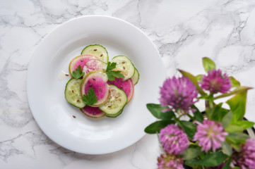 Healthy salad made from sliced watermelon radish (chinese daikon), cucumber and flax seeds on marble table. Top view. Detox fresh vegetables food. 