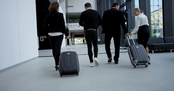 Business people walking with wheeled bags