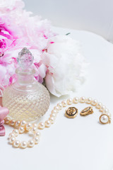 Lfestyle with pink peony flowers, glamour bottles and jewellery close up