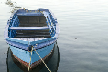 Fototapeta na wymiar blue wooden rowboat on still water