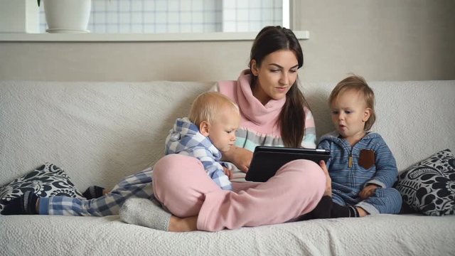Mother and two baby sons playing with digital tablet