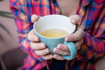 Woman hands holding a cup of green tea. 