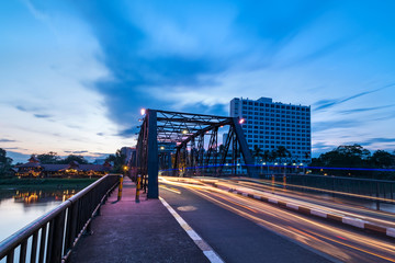 The historical iron bridge at Chiangmai city skyline at Ping river at dusk. Chiangmai , Thaland. Long exposure photograph.