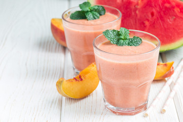 Watermelon, peach, mint and coconut milk smoothie in glass on white wooden background, horizontal, copy space