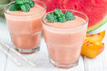 Foto op Plexiglas Milkshake Watermelon, peach, mint and coconut milk smoothie in glass on white wooden background, horizontal