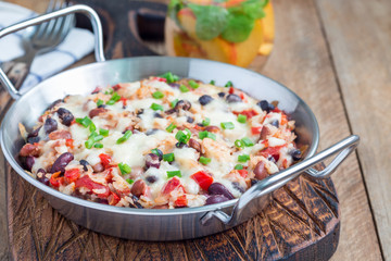 Baked rice casserole with different kind of beans, cheese and paprika, in metal baking dish, horizontal, copy space