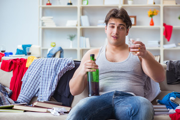Young man student drunk drinking alcohol in a messy room