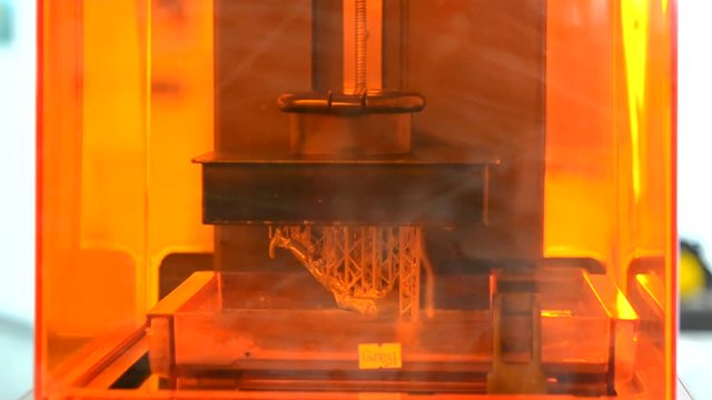 Stereolithography DPL 3d printer create detail and liquid drips, platform slowly move with liquid close-up. Progressive modern additive technology 3D printing, create scaled model by UV polymerization