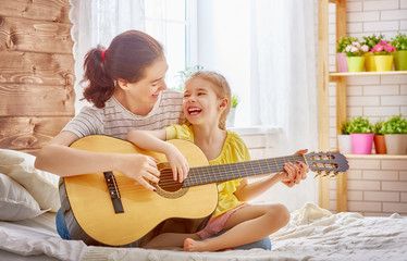 woman playing guitar for child girl