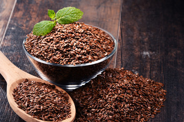Composition with bowl of flax seeds on wooden table