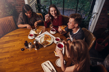 High angle shot of group of best friends having dinner at round table together talking and smiling...