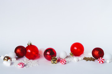 Christmas decorations on white background. Transparent red and glitter baubles ornaments, peppermint swirl candy, gold bells, marshmallow