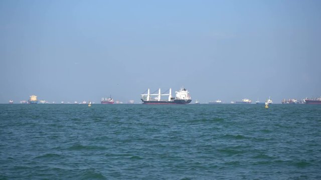 Cargo ships floats on waves in the blue sea.