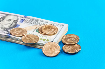 US coins with stack of american one hundred dollars on a blue. Close up.