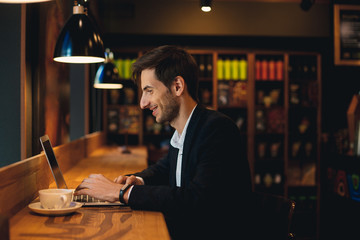 Smiling man chatting on laptop having coffee