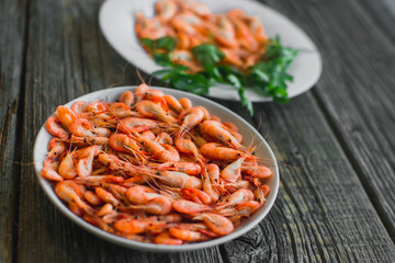 on a wooden background, white plate with shrimps