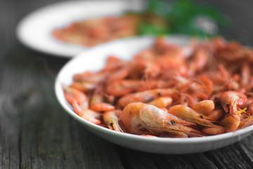 on a wooden background, white plate with shrimps