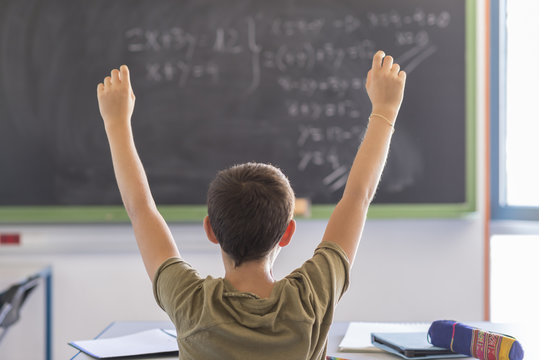 Student with hands up in classroom during a lesson