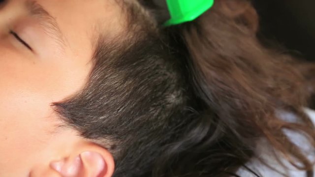 Mother treating son's hair against lice