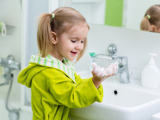 cute child washing hands in bathroom