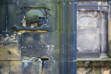 Fototapeta premium Stone skull and bone sculpture on a wall in a graveyard