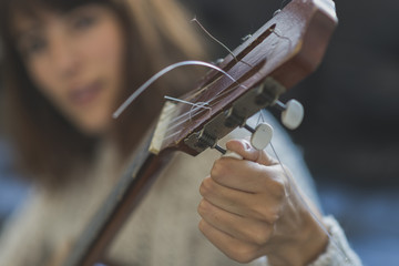Beautiful young woman sitting on sofa playing guitar