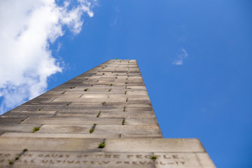 Perspective view from below of an obelisk in a cloudy sky