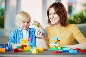 Obraz na płótnie Canvas Mother playing colorful construction blocks with her son