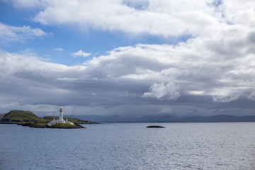 White lighthouse on a Scottish island with a cloudy sky