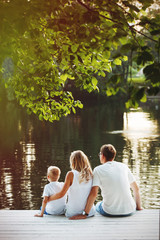 Family sitting near water and watching the lake at sunset