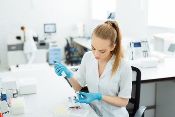 Pipette dropping a sample in a test tube. Laboratory assistant analyzing blood in lab. DNA analysis