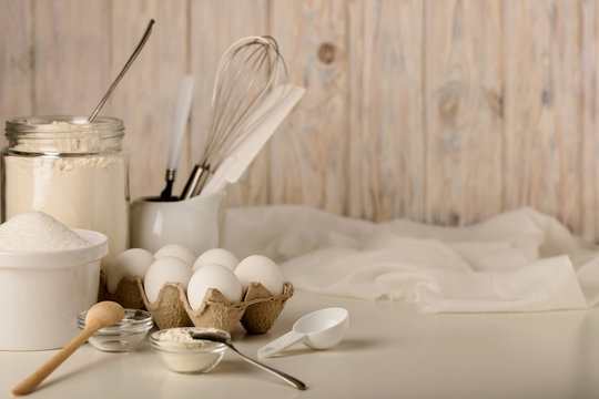 Kitchen utensils and tools for homemade baking on a light wooden background.