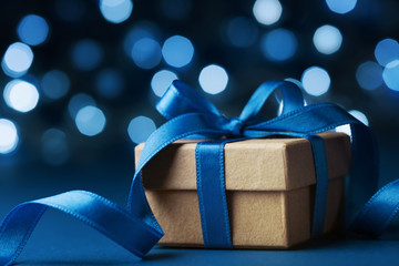 Christmas gift box or present against blue bokeh background. Holiday greeting card.