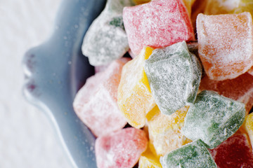 sweets and desserts, macro food, multi-colored oriental rahat tortoise, Turkish delight  in powdered sugar on a light background
